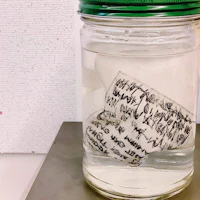 a jar of water with a piece of paper in it