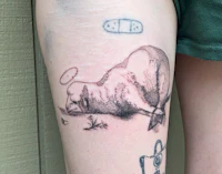 a woman has a tattoo of a sheep on her thigh