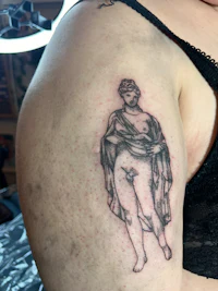 a woman has a tattoo of a woman with a cloak on her arm