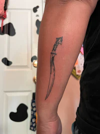 a tattoo of a knife on a person's forearm