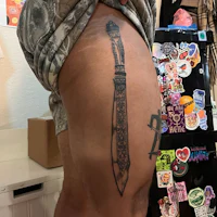 a man with a knife tattoo on his thigh