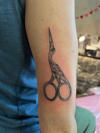a tattoo of a pair of scissors on a person's arm