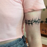 a woman with a barbed wire tattoo on her arm